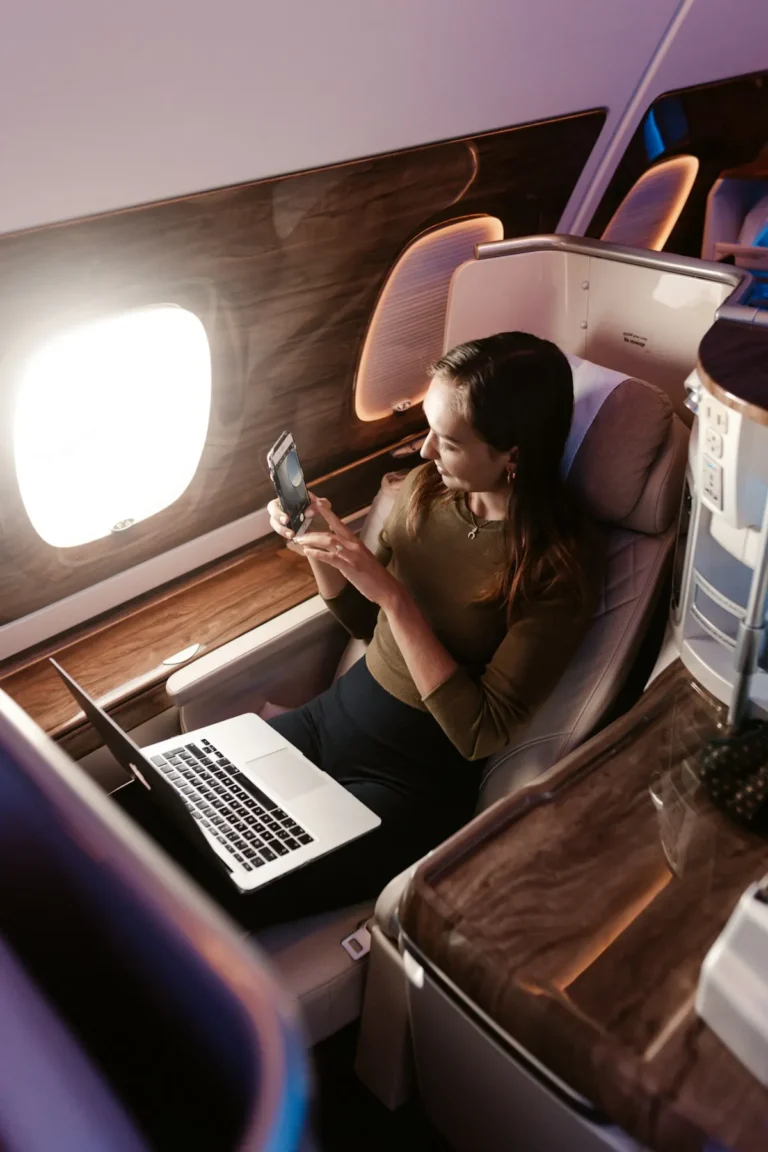 A traveler in a business class seat taking a photo out of the window
